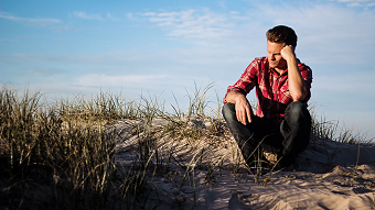 Man sitting on the beach, deep in thought